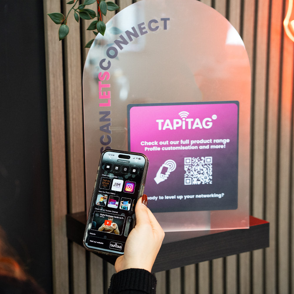 Person using a smartphone with a Tapitag app in front of a Tapitag display.