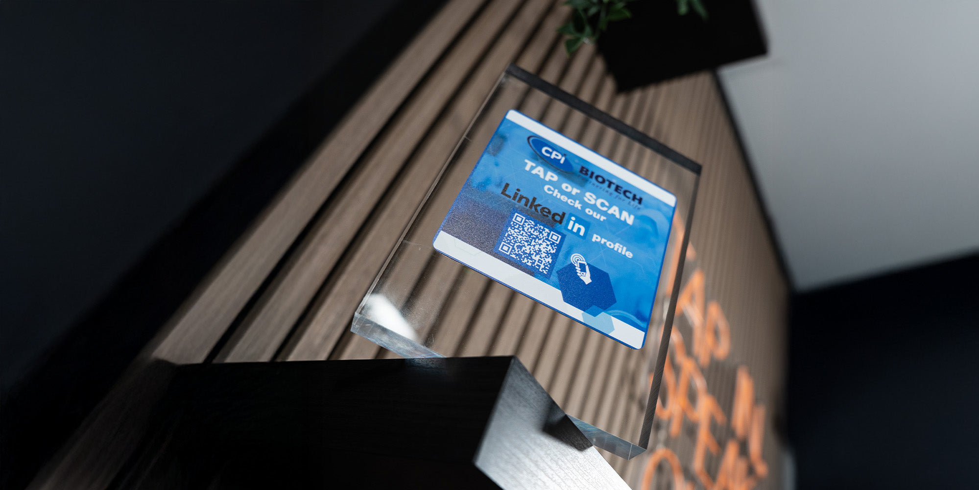 acrylic display case with a blue sign and QR code on a wooden surface