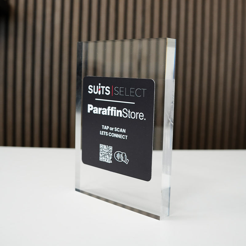 Clear acrylic sign with 'SUITS SELECT Paraffin Store' branding on a reflective surface with nfc tag