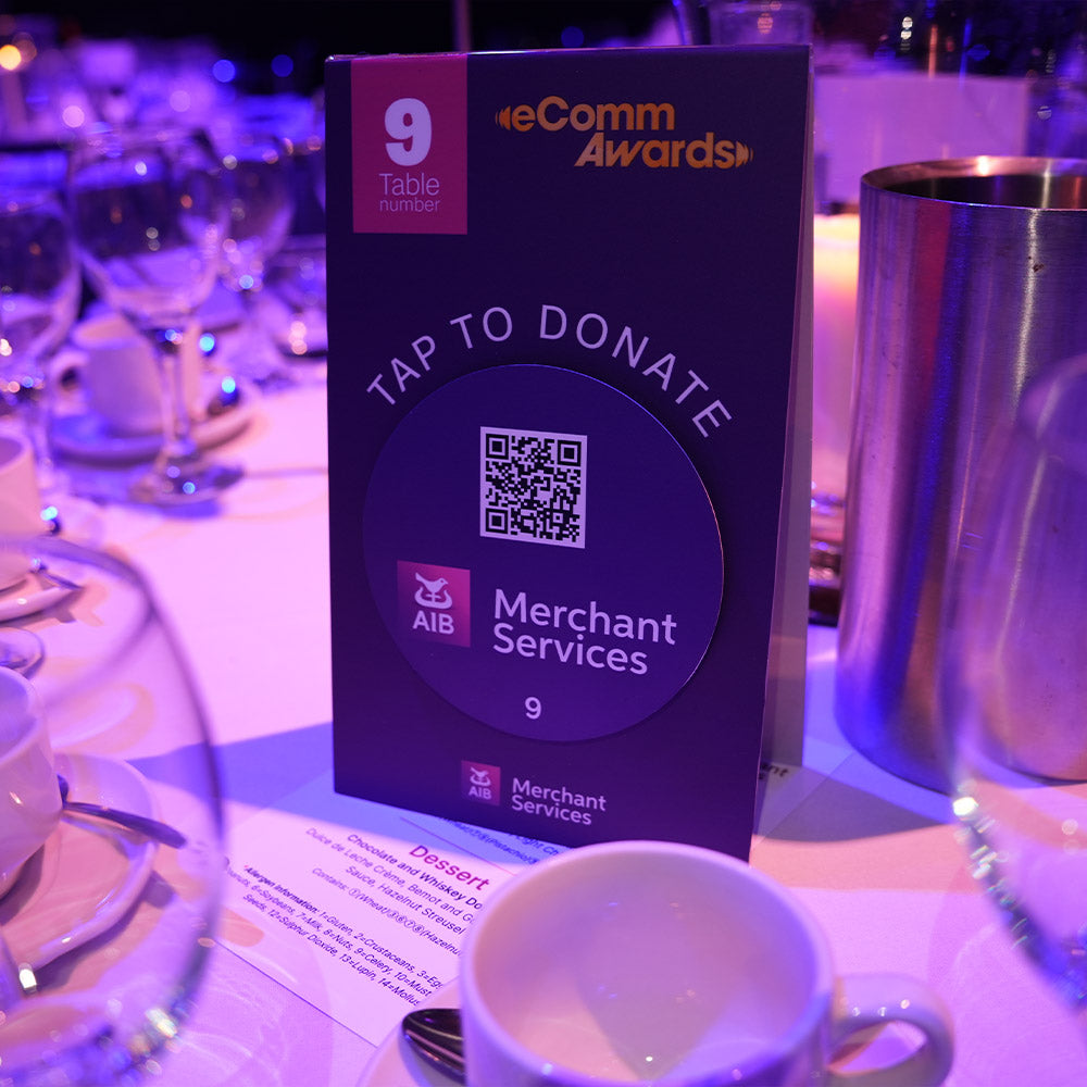 TAPiTAG gamified donations Screen displaying instructions on how to donate at the Irish eCommerce Awards 2025 event. Donation card for eComm Awards on a table with a cup and saucer in the foreground