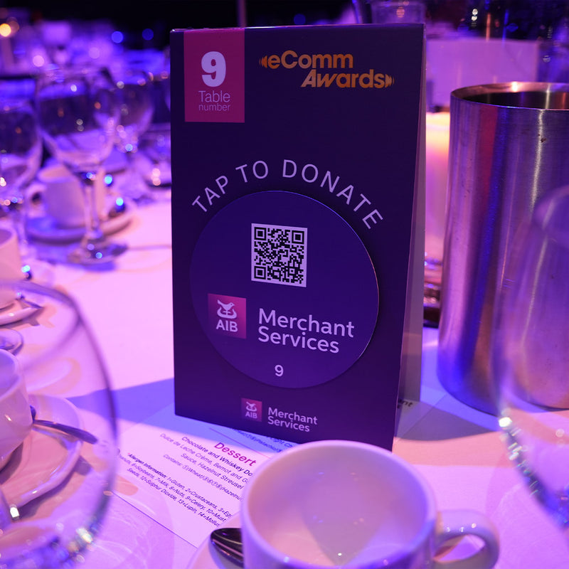 TAPiTAG gamified donations Screen displaying instructions on how to donate at the Irish eCommerce Awards 2025 event. Donation card for eComm Awards on a table with a cup and saucer in the foreground