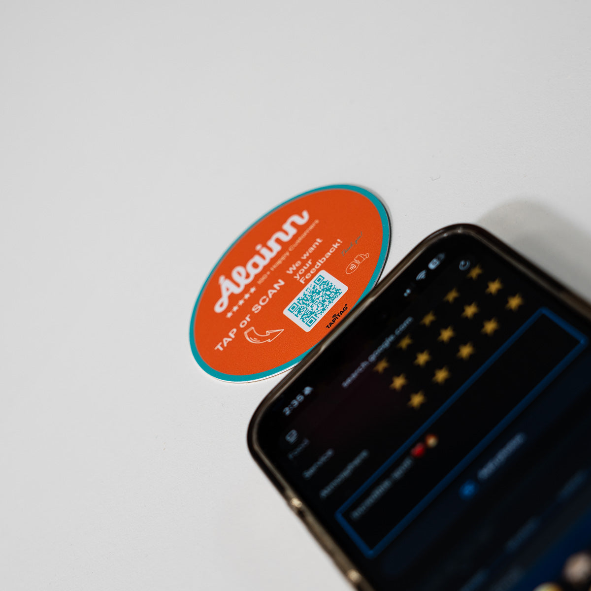 TAPiTAG Google review tag for Alainn Orange NFC Tag with a QR code on a smartphone screen
