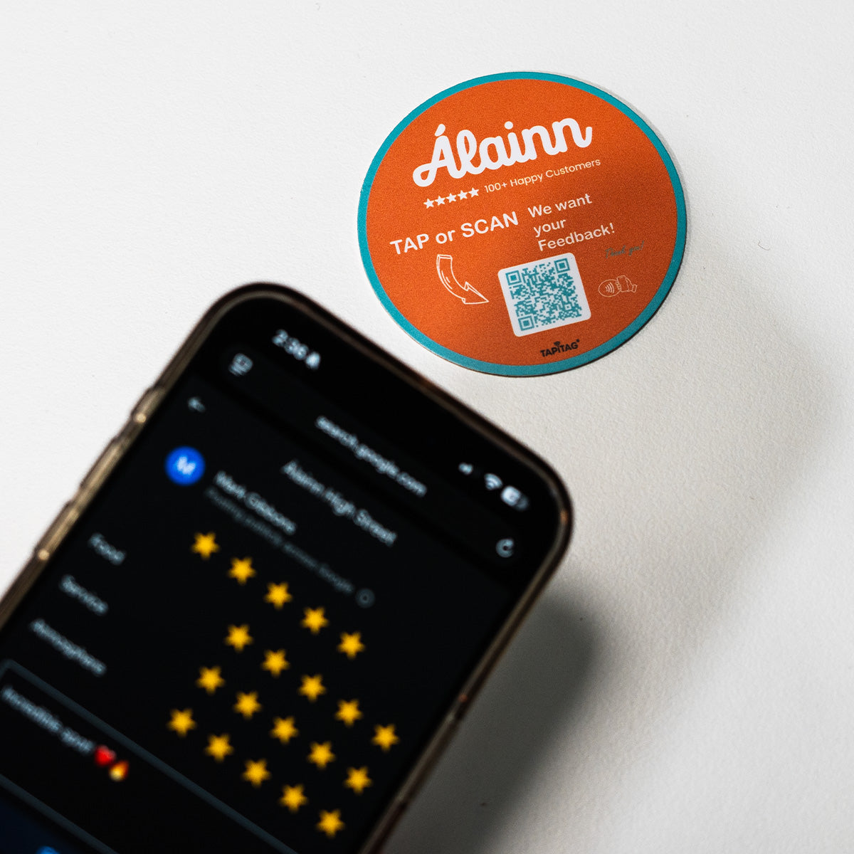 TAPiTAG Google review tag for Alainn Orange NFC Tag with a QR code on a smartphone screen