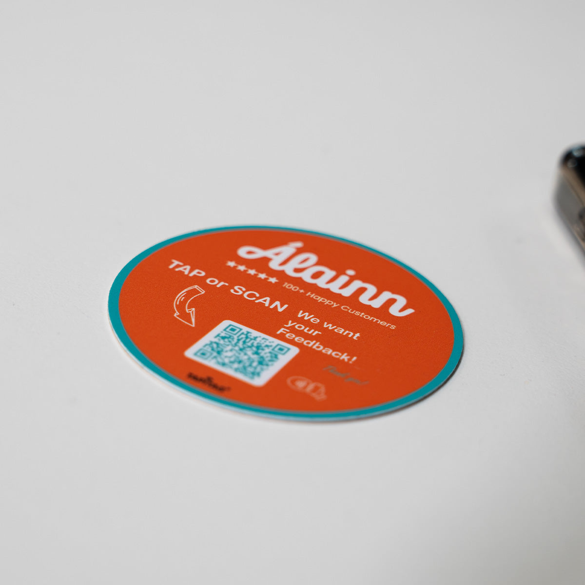 TAPiTAG Google review tag for Alainn Orange NFC Tag with a QR code on a smartphone screen