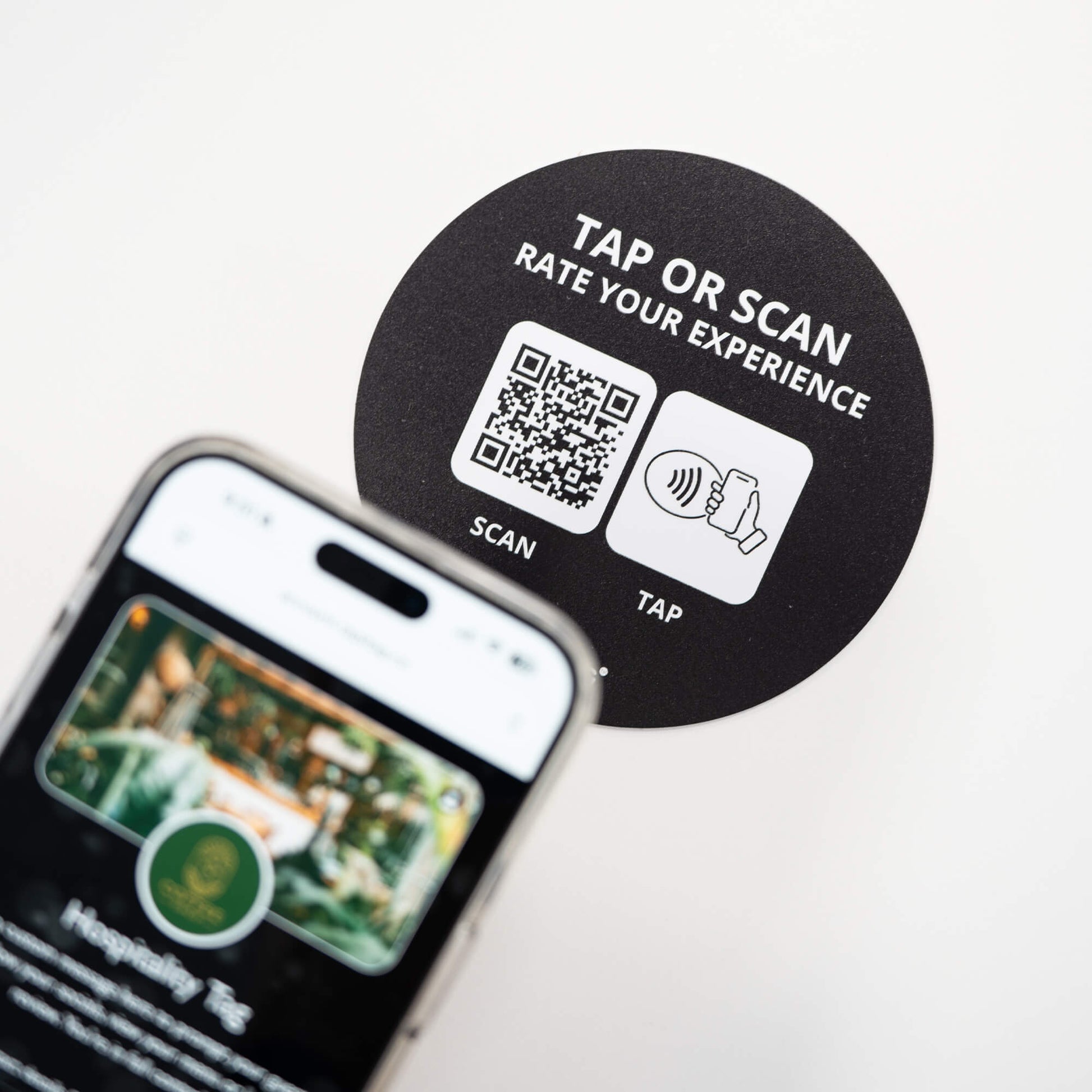 Person tapping TAPiTAG NFC hospitality tag with smartphone to access digital business profile instantly