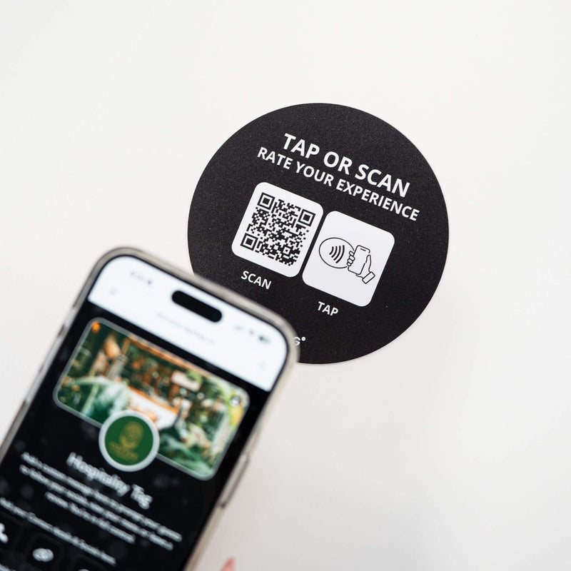 Person tapping TAPiTAG NFC hospitality tag with smartphone to access digital business profile instantly