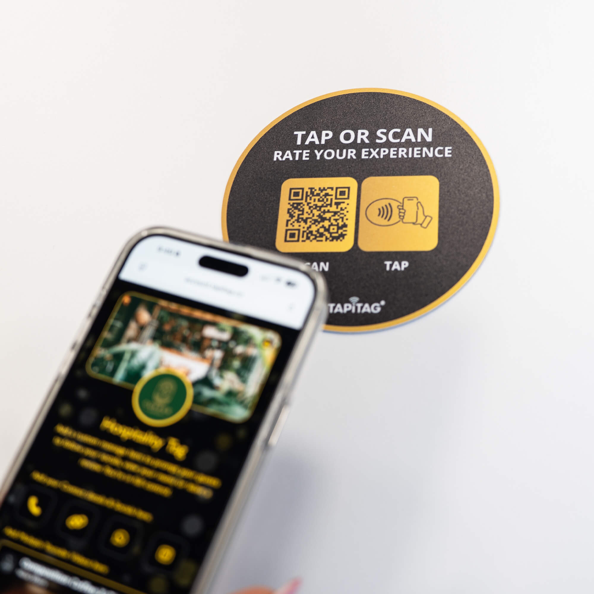 Person tapping TAPiTAG NFC hospitality tag with smartphone to access digital business profile instantly