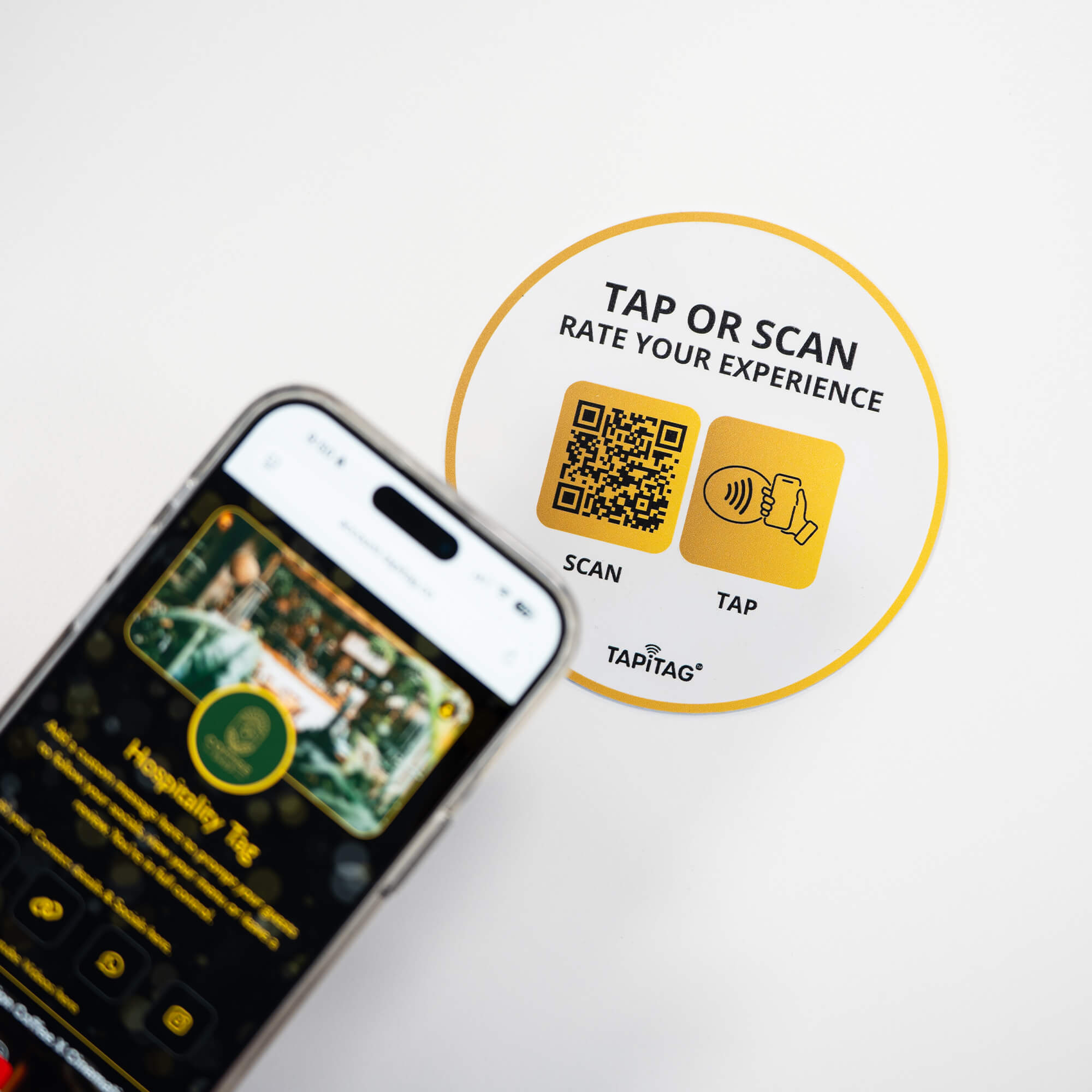 Person tapping TAPiTAG NFC hospitality tag with smartphone to access digital business profile instantly