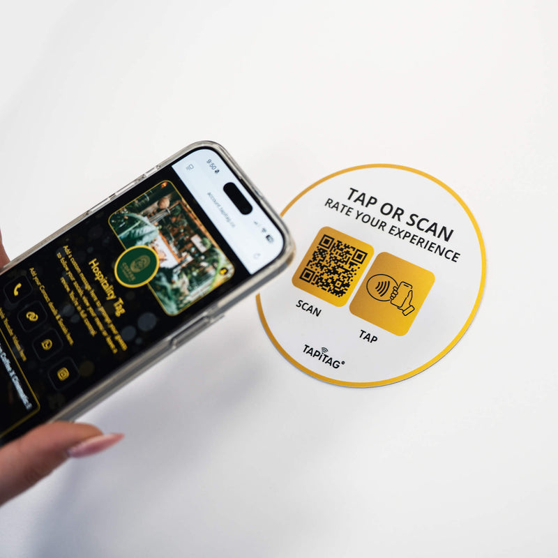Person tapping TAPiTAG NFC hospitality tag with smartphone to access digital business profile instantly