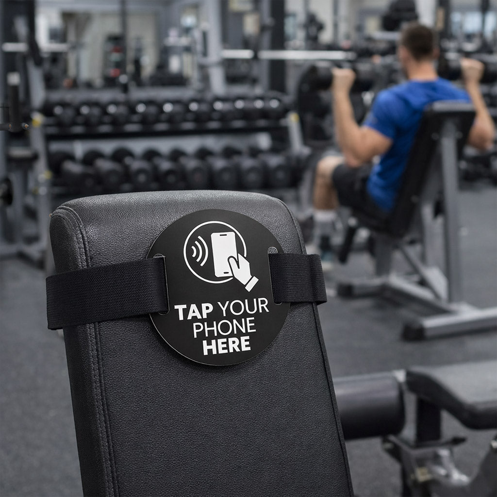 “TAPiTAG NFC gym equipment tag attached to weight bench in fitness centre.”