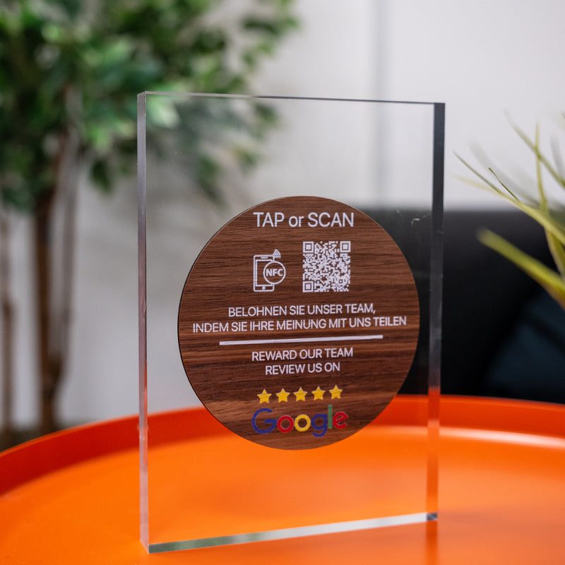 Wooden TAPiTAG NFC TAG with QR code and text on a CLEAR ACYRLIC surface