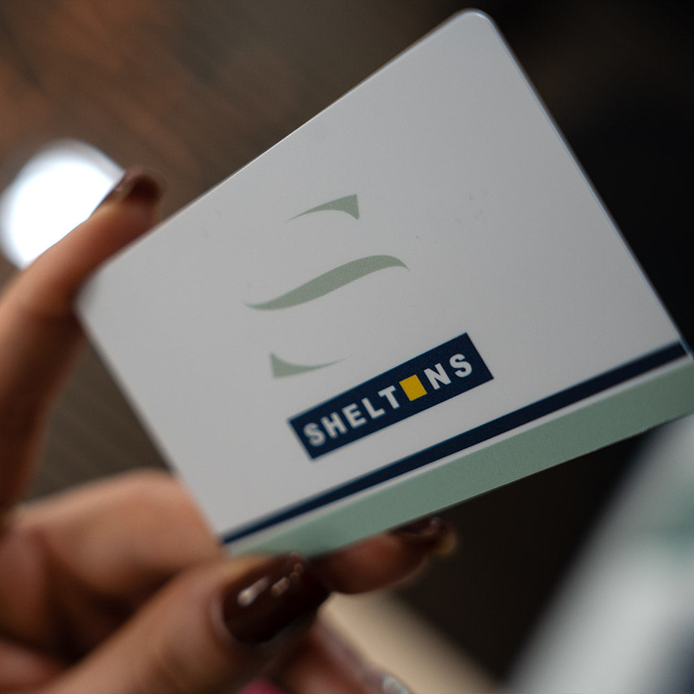 Hand holding a TAPiTAG Digital Business card  white box with 'SHELTONS' logo