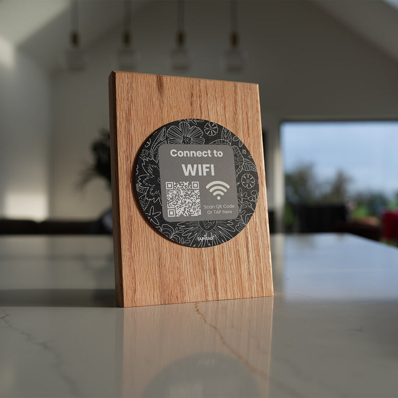 TAPiTAG wooden NFC WiFi stand on a countertop allowing guests to tap or scan a QR code to connect to WiFi instantly.