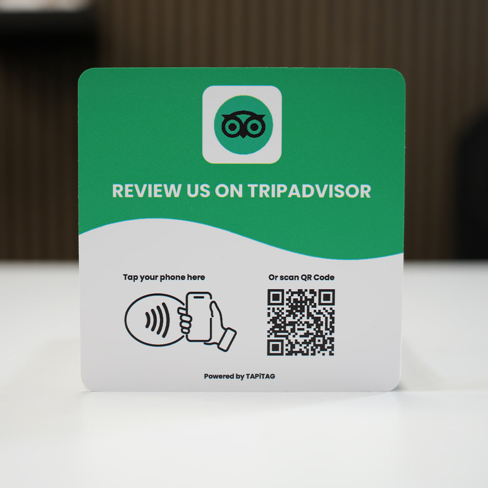 TripAdvisor NFC review plate by TAPiTAG with QR code, allowing customers to tap or scan to instantly review a business on TripAdvisor , displayed on a white counter.