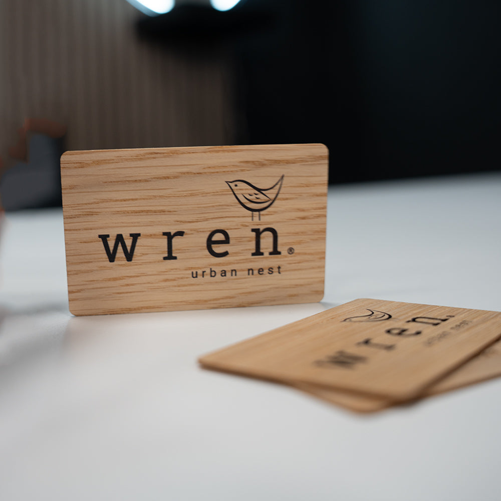 Wooden digital business card with 'wren urban nest' branding held by a hand against a dark background