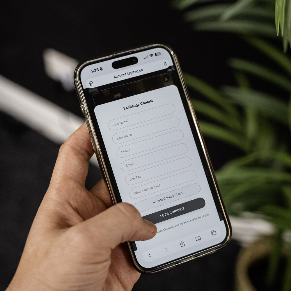 Hand holding a smartphone displaying an app interface with a blurred background TAPiTAG Digital Business Card 