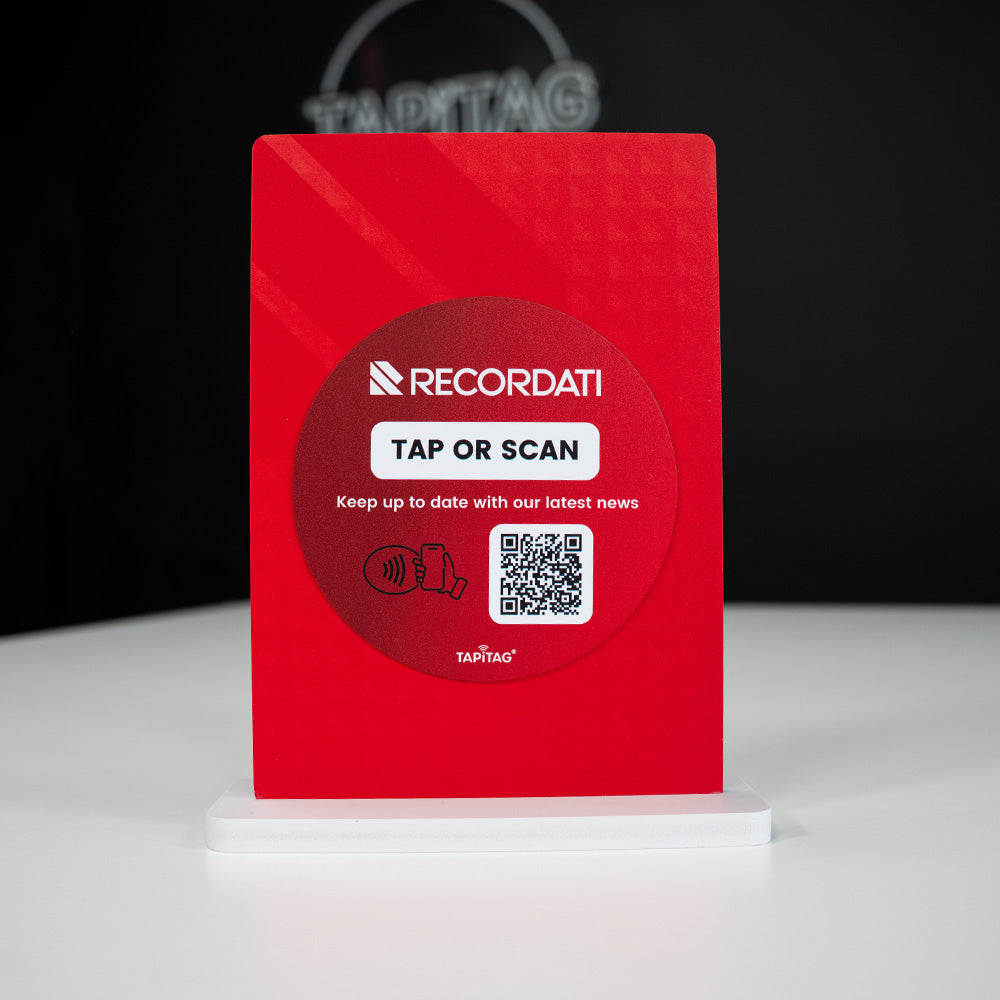 Red smart display stand with Recordati branding and QR code on a white stand against a dark background
