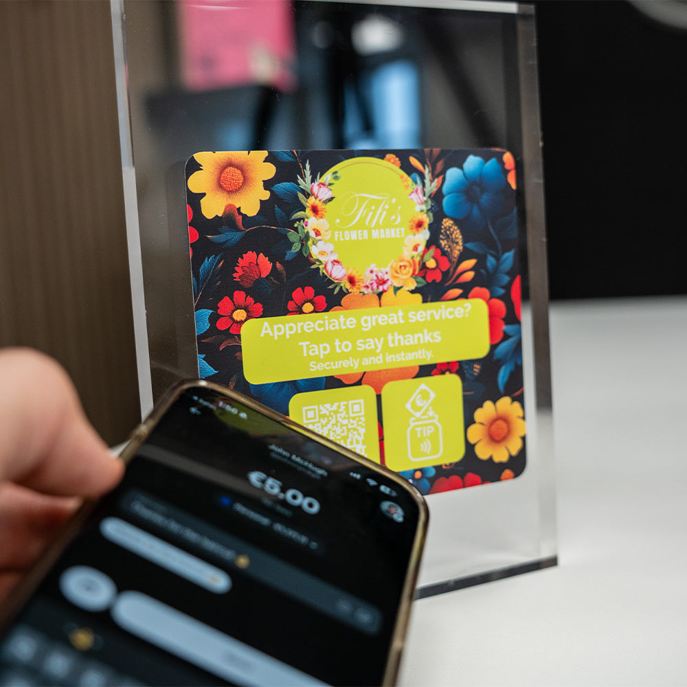 TAPiTAG TIP Floral-themed NFC TAG card with QR code being scanned by a smartphone.