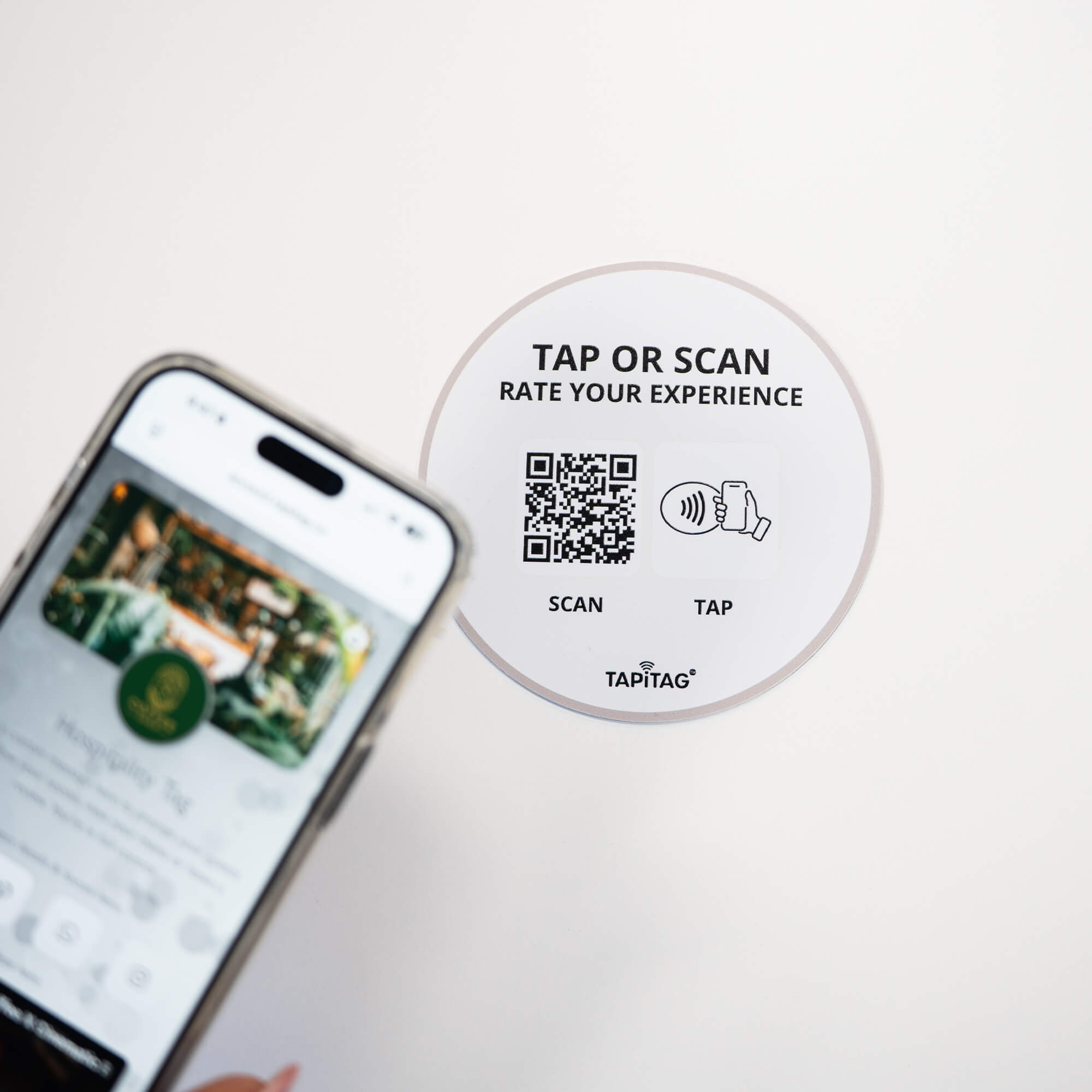 Person tapping TAPiTAG NFC hospitality tag with smartphone to access digital business profile instantly