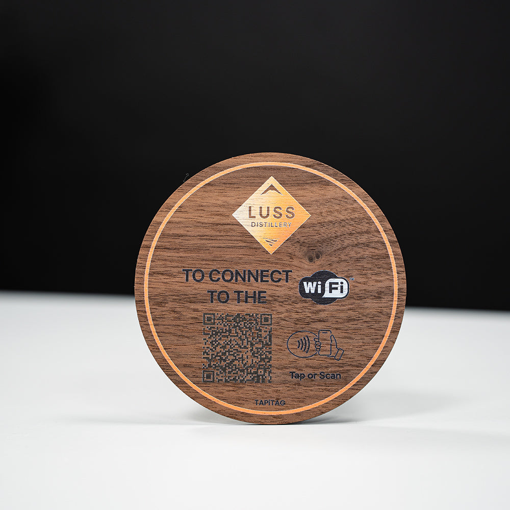 Wooden coaster with QR code and Wi-Fi connection information on a black background