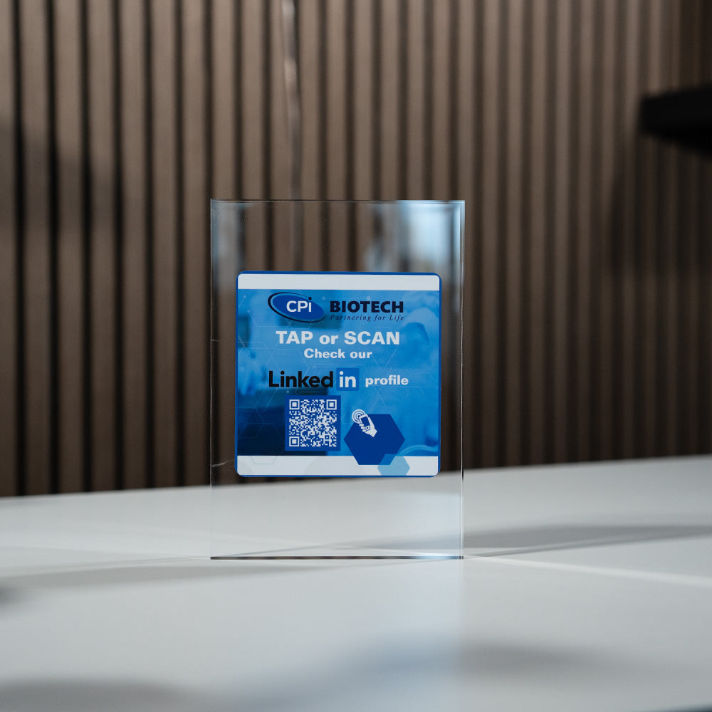 Clear acrylic sign with CPI Biotech branding and LinkedIn QR code on a reflective surface.