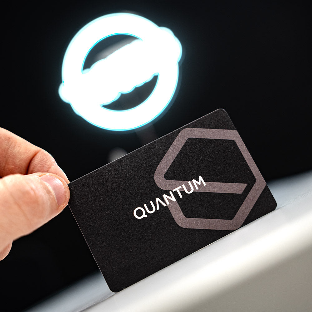 Black card with 'QUANTUM' logo held by a hand against a dark background with a glowing logo. TAPiTAG Digital Business Card Bamboo