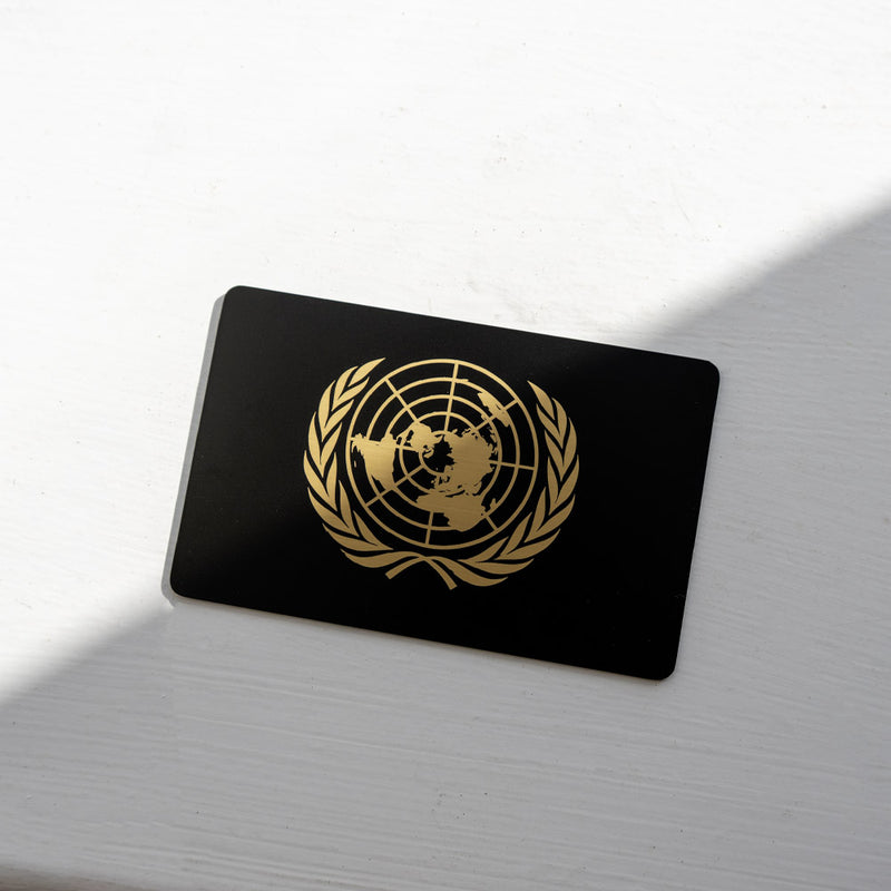 Black metal business card with gold United Nations logo on a white surface