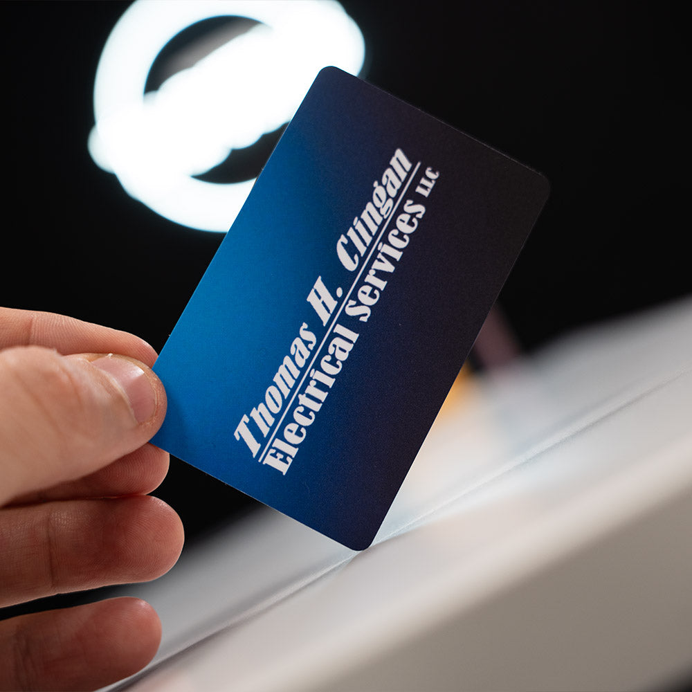 blue TAPiTAG NFC-Enabled Digital Business Card  Hand holding a blue business card with 'Thomas H. Clingan Electrical Services LLC' text.