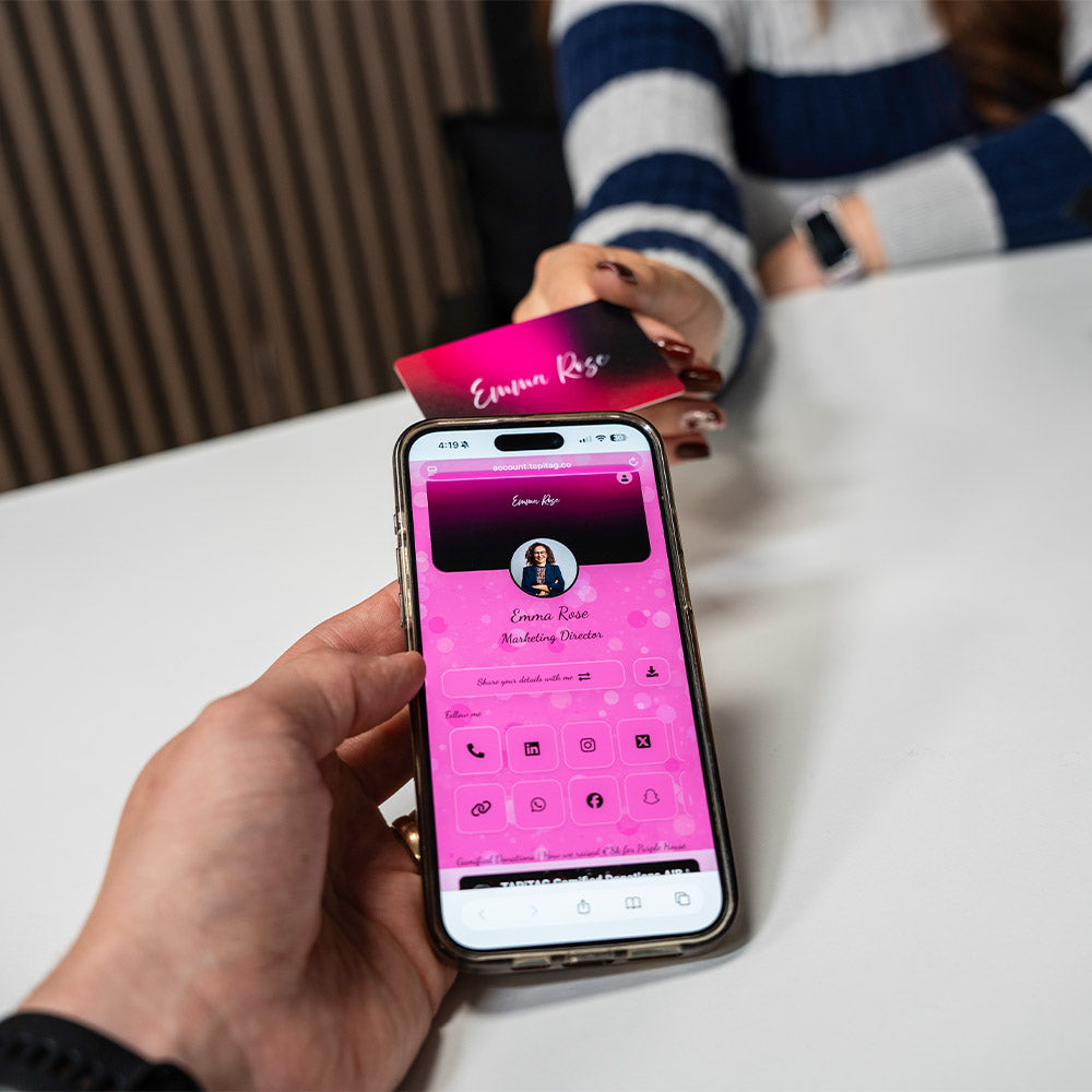 Person holding a phone with a pink app interface, interacting with a TAPiTAG Digital Business Card .