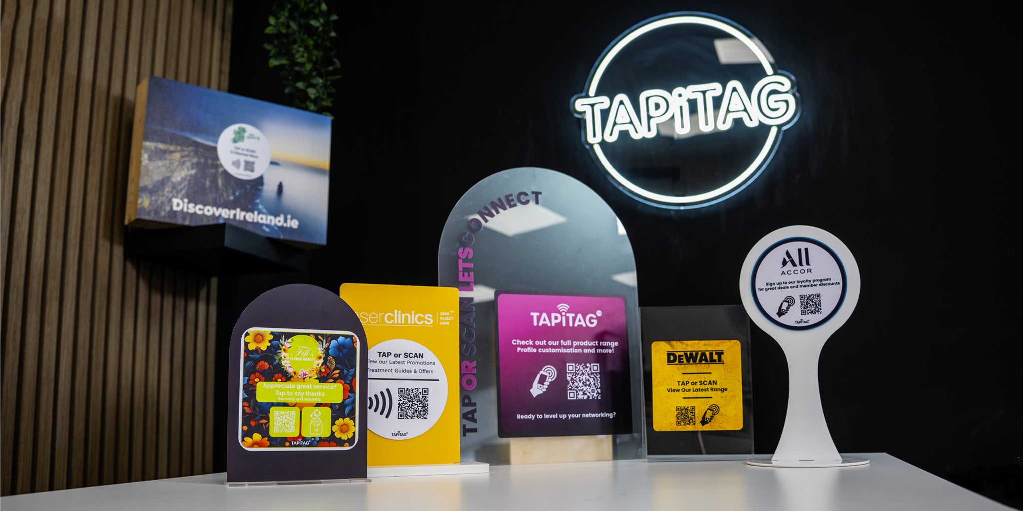 Collection of branded QR code signs with visible 'Tapitag' logo on a dark background