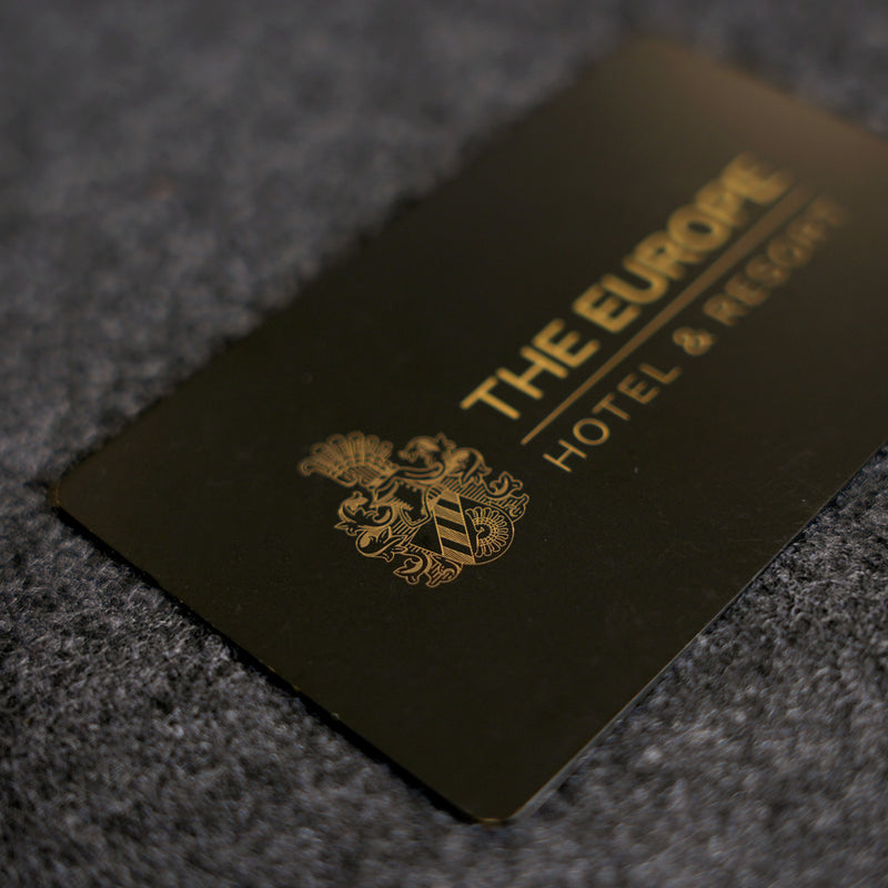 Black metal business card with gold United Nations logo on a grey surface