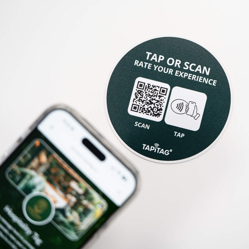 Person tapping TAPiTAG NFC hospitality tag with smartphone to access digital business profile instantly