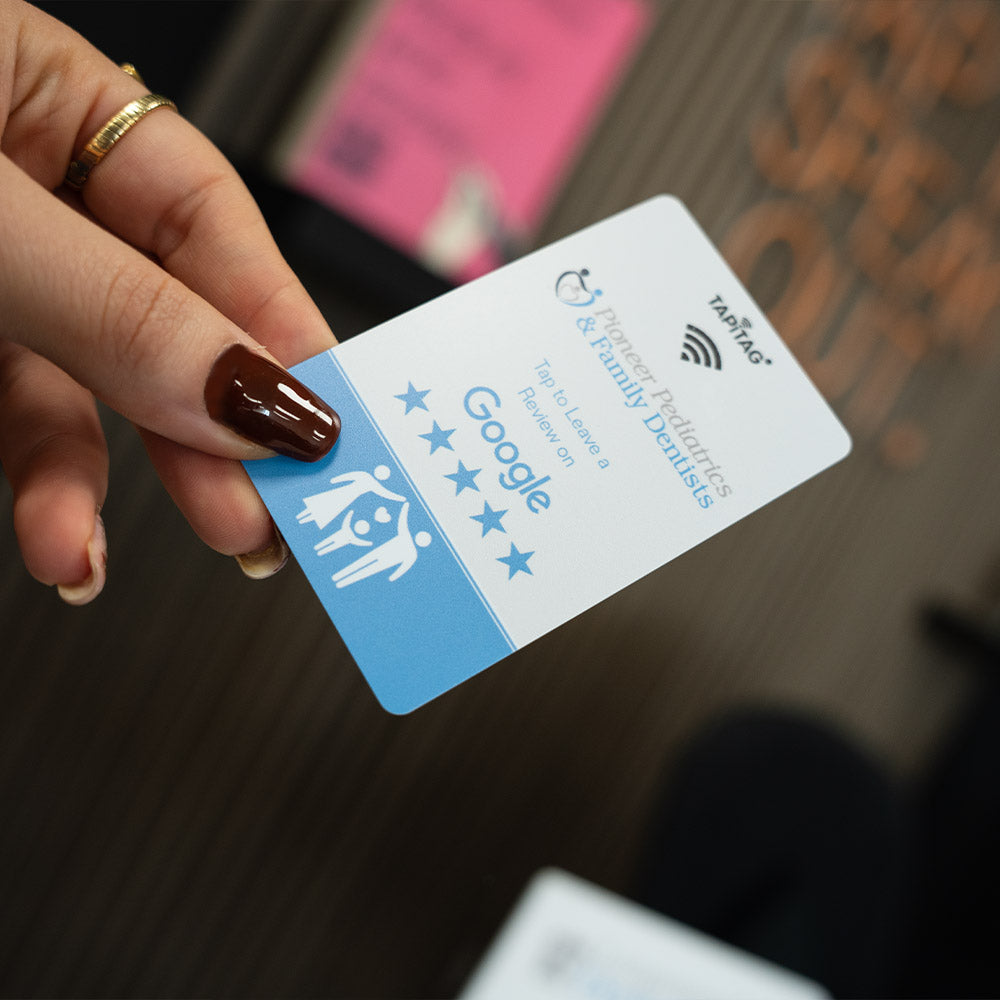Hand holding a card with Google and Family-friendly Facilities logos on a blurred background