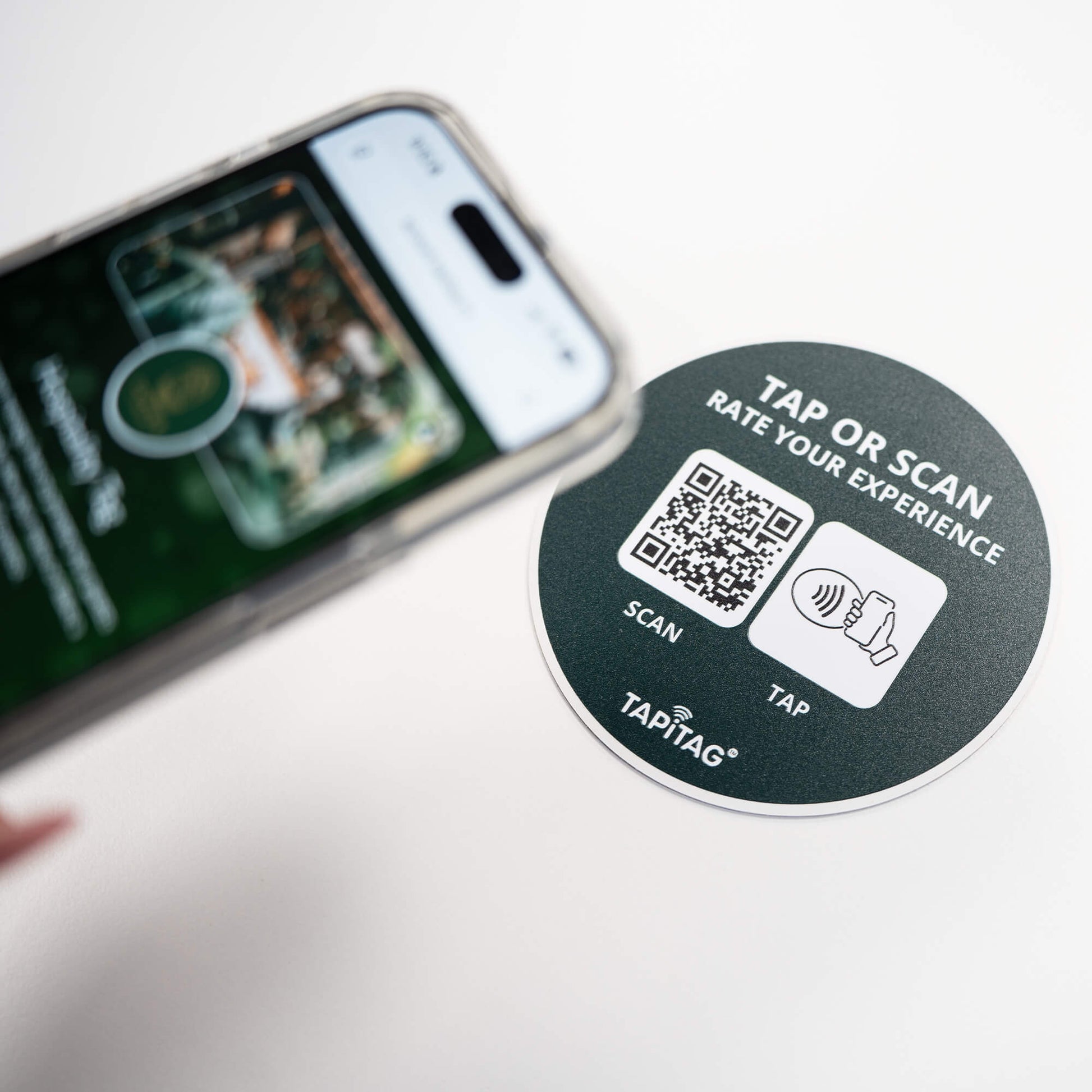 Person tapping TAPiTAG NFC hospitality tag with smartphone to access digital business profile instantly