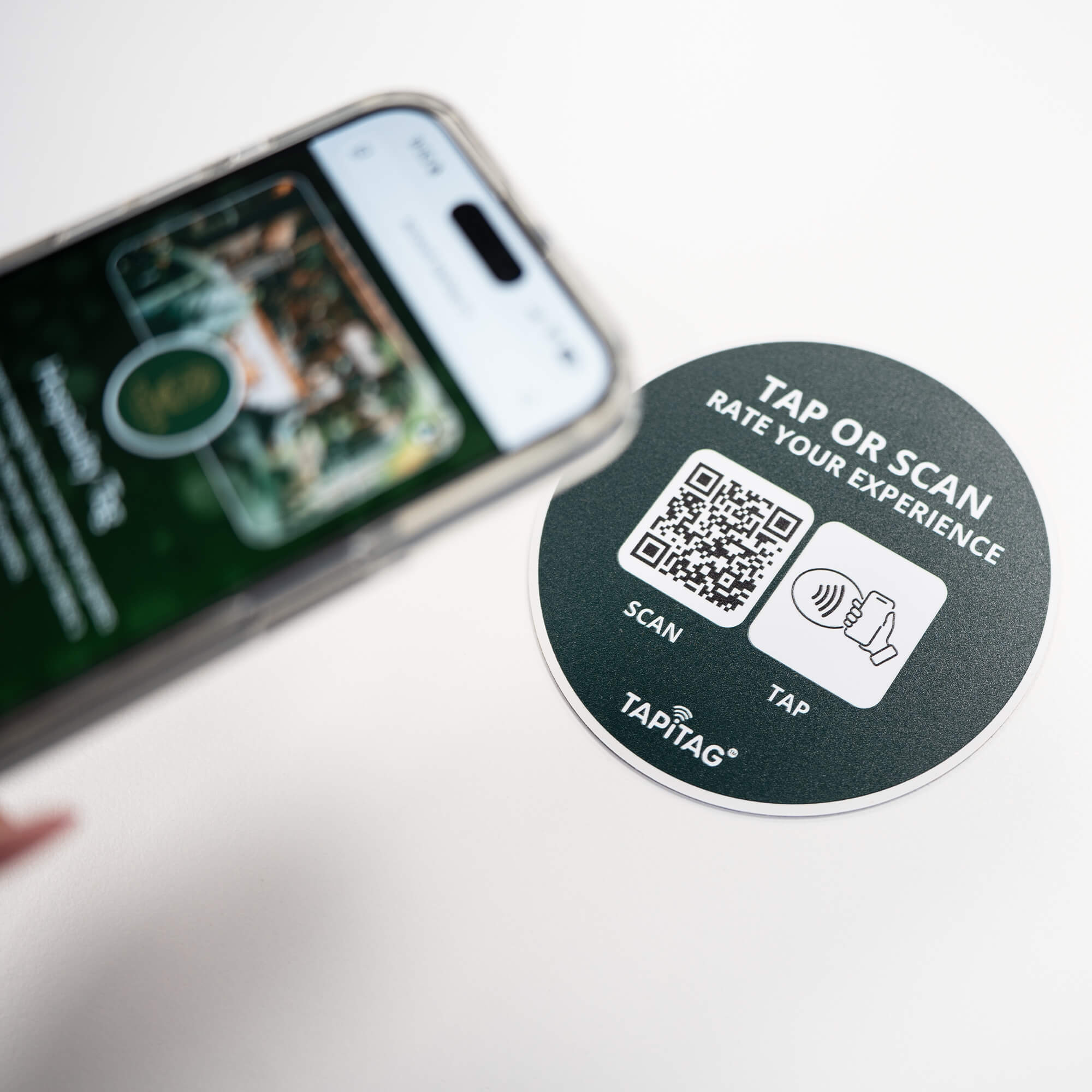 Person tapping TAPiTAG NFC hospitality tag with smartphone to access digital business profile instantly