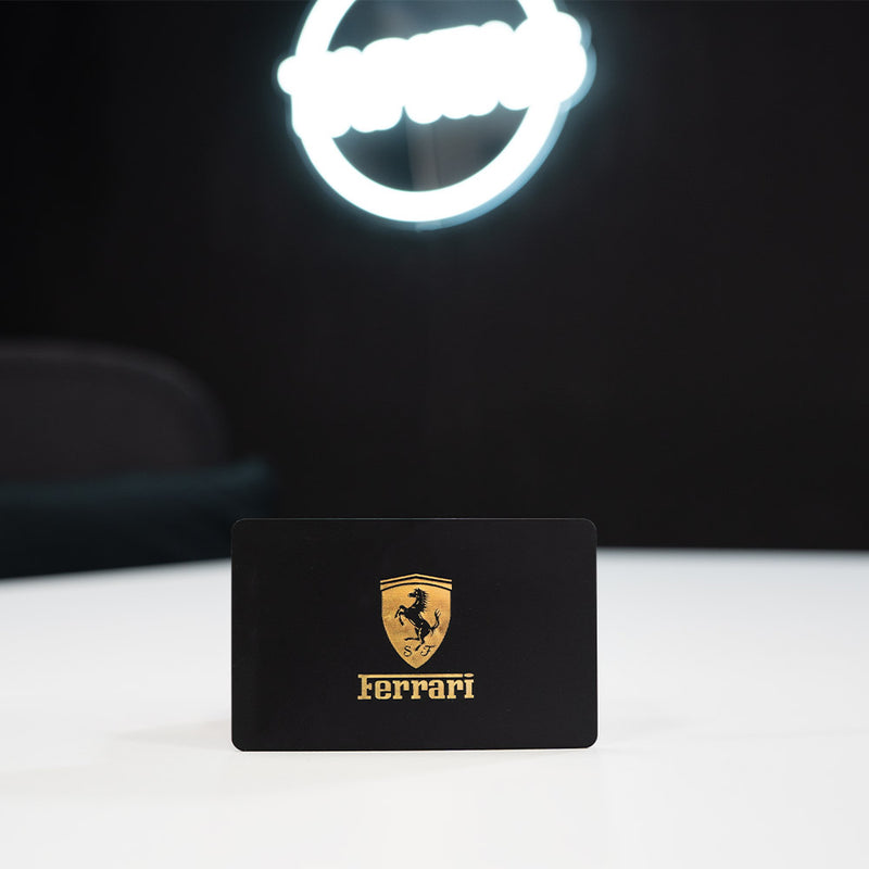 Plastic TAPiTAG Digital Business Card, also known as an NFC Business Card Ferrari logo on a black card with a neon sign in the background