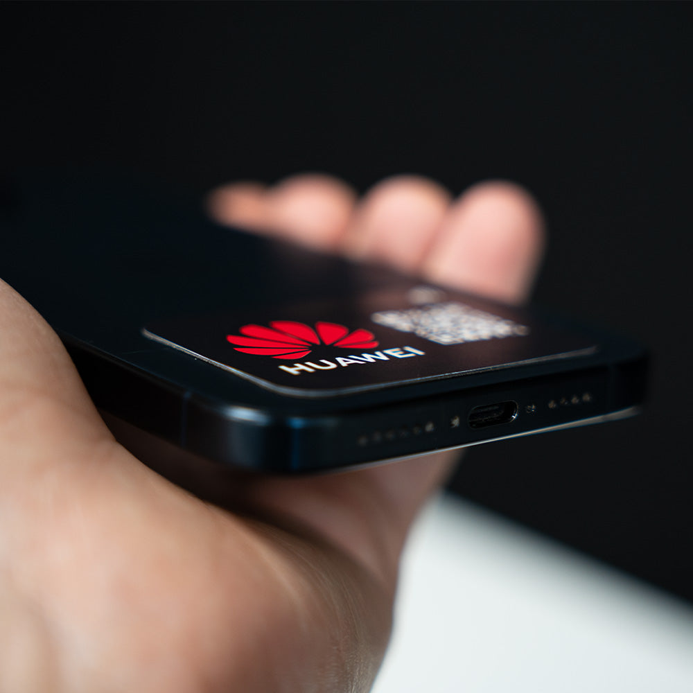 Hand holding a Huawei smartphone with a blurred background. TAPiTAG NFC QR MINICARD NFC-Enabled Digital Business Card