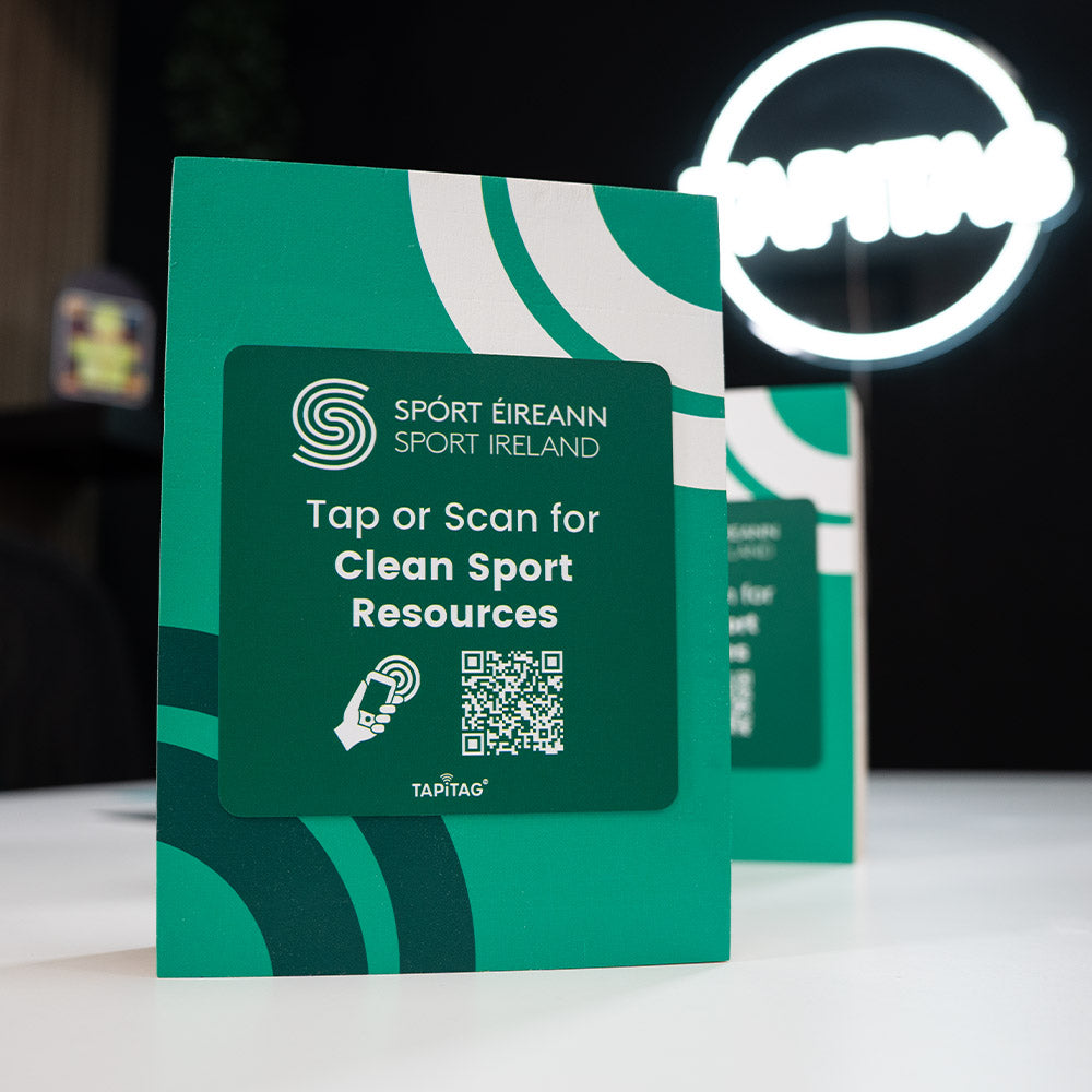 TAPITAG Green nfc tag wood display stand with Sport Ireland branding and QR code on a white surface.