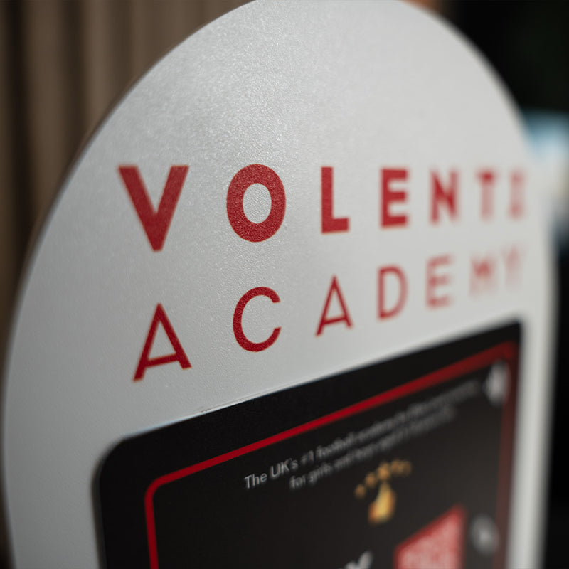Close-up of a device with 'Volentis Academy' branding on a blurred background