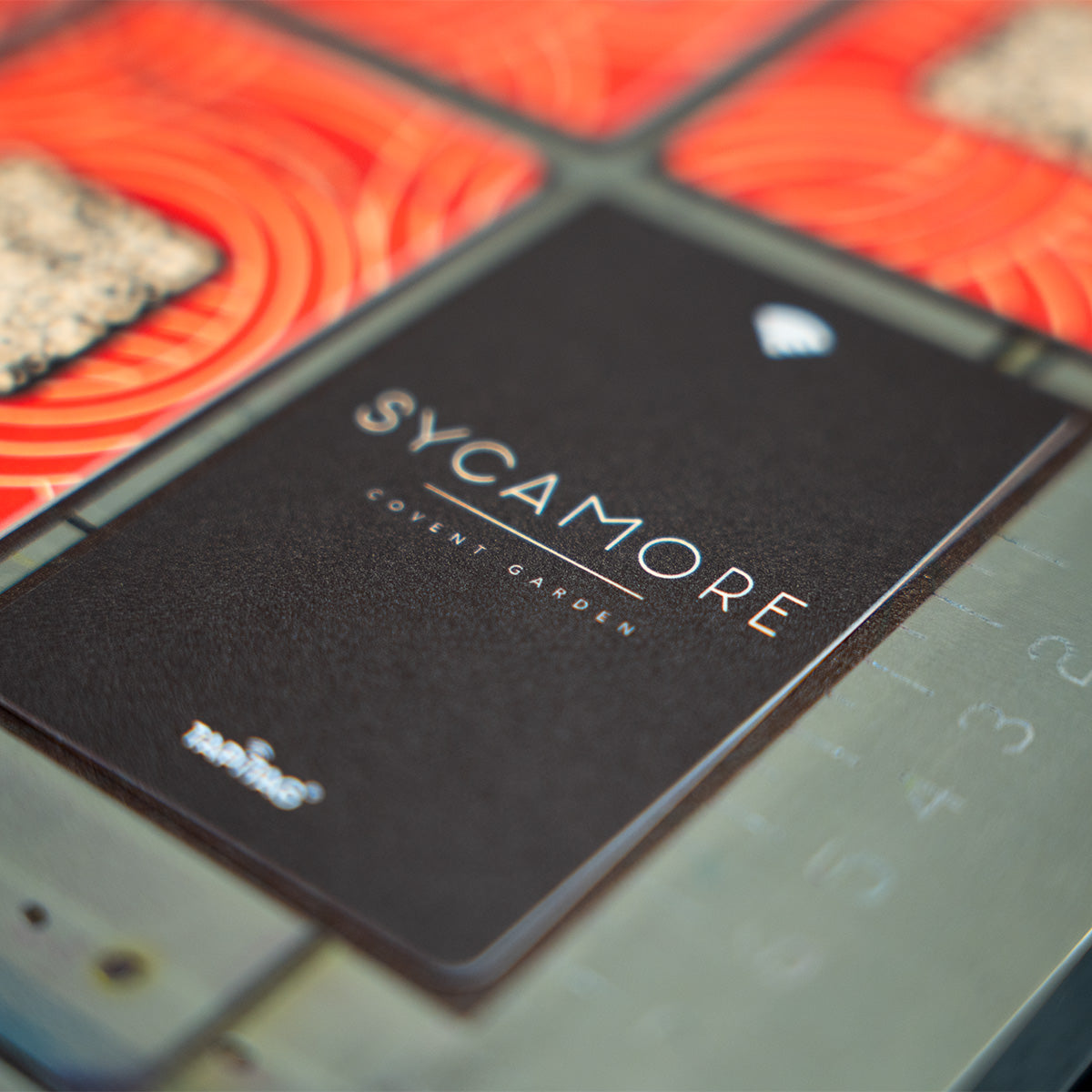 Close-up of a tapitag google review card with 'Sycamore' branding on a textured surface.