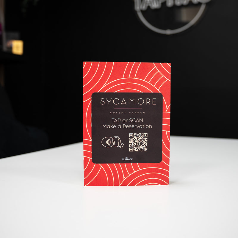 Red and black TAPiTAG WOOD smart display stand with QR code and 'Sycamore' branding on a white surface.