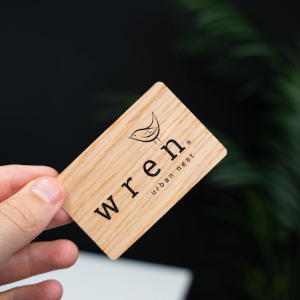 Wooden digital business card with 'wren urban nest' branding held by a hand against a dark background